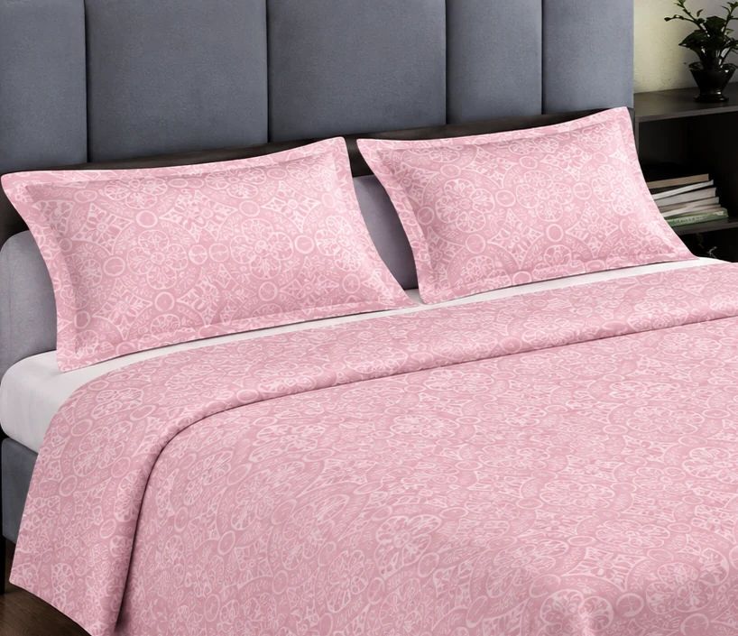 Soft pink bedding and pillows arranged on a bed