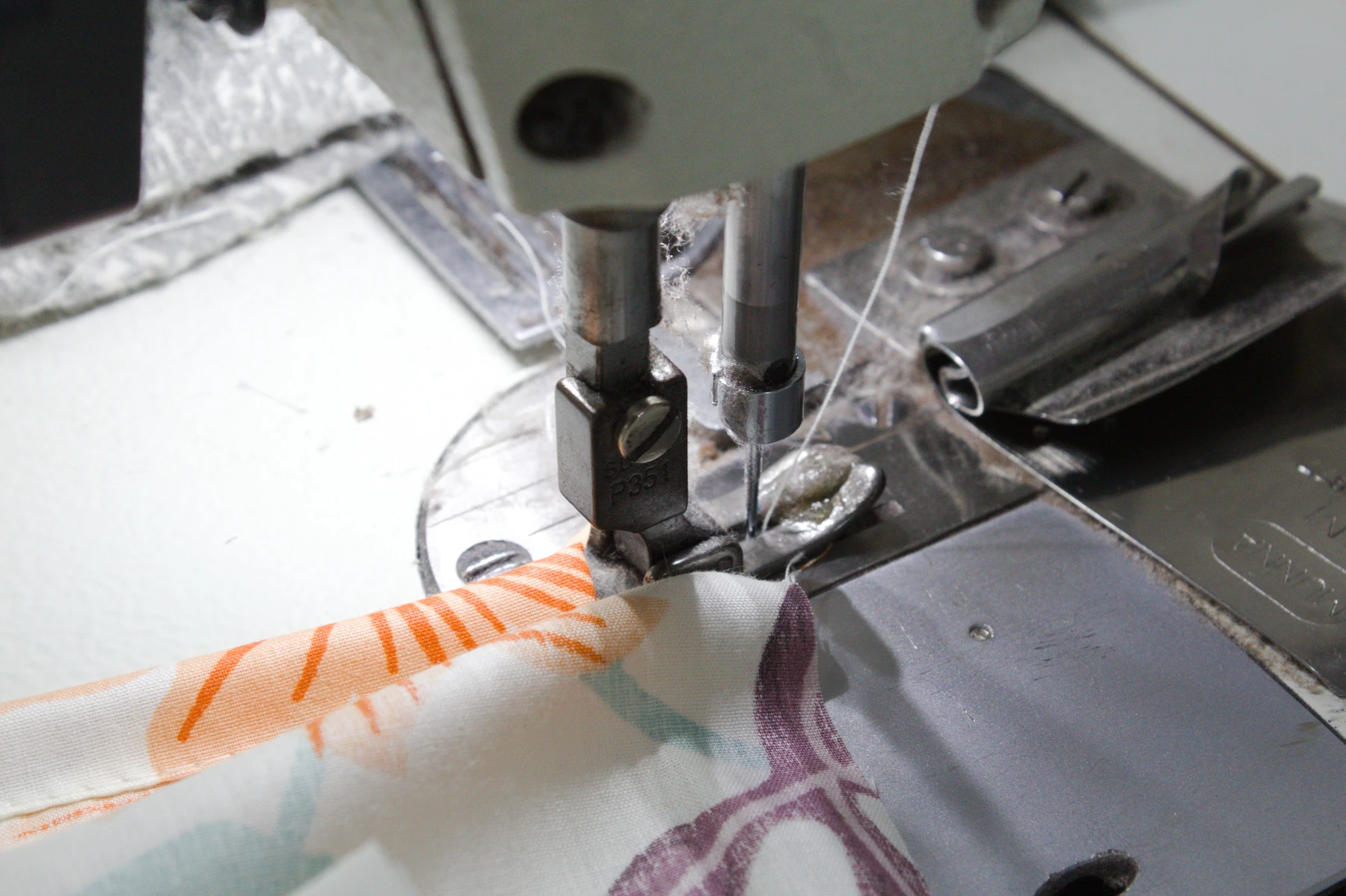 Close-up of a sewing machine stitching printed bedsheet fabric