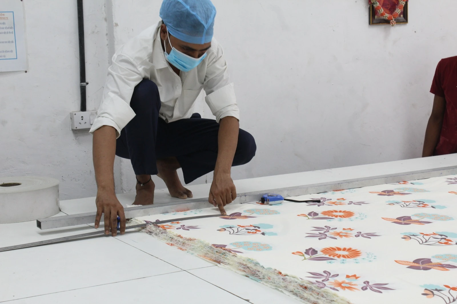 A worker measuring and cutting printed bedsheet fabric